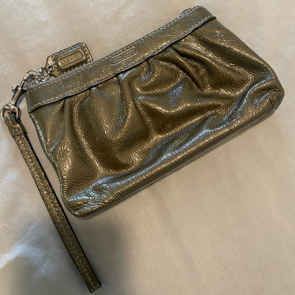 This is a silver/grey patent leather Coach wristlet.